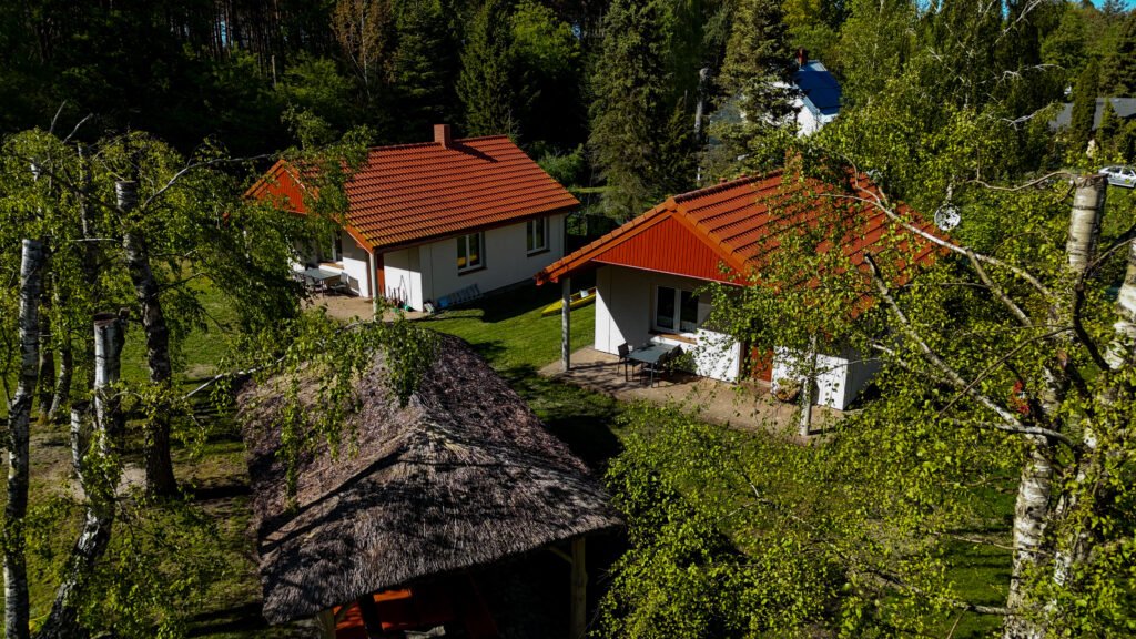 Widok na domki i altanę wśród drzew – spokojna, zielona przestrzeń.