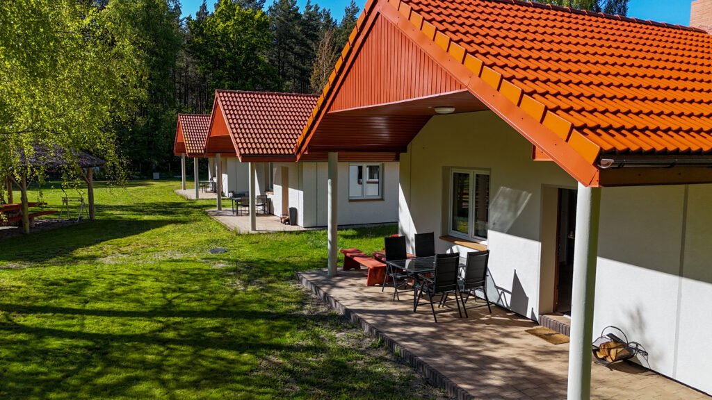 Widok na domki i altanę wśród drzew – spokojna, zielona przestrzeń.
